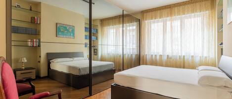A bedroom with a large bed, a desk, a chair, a bookshelf, and a map on the wall.