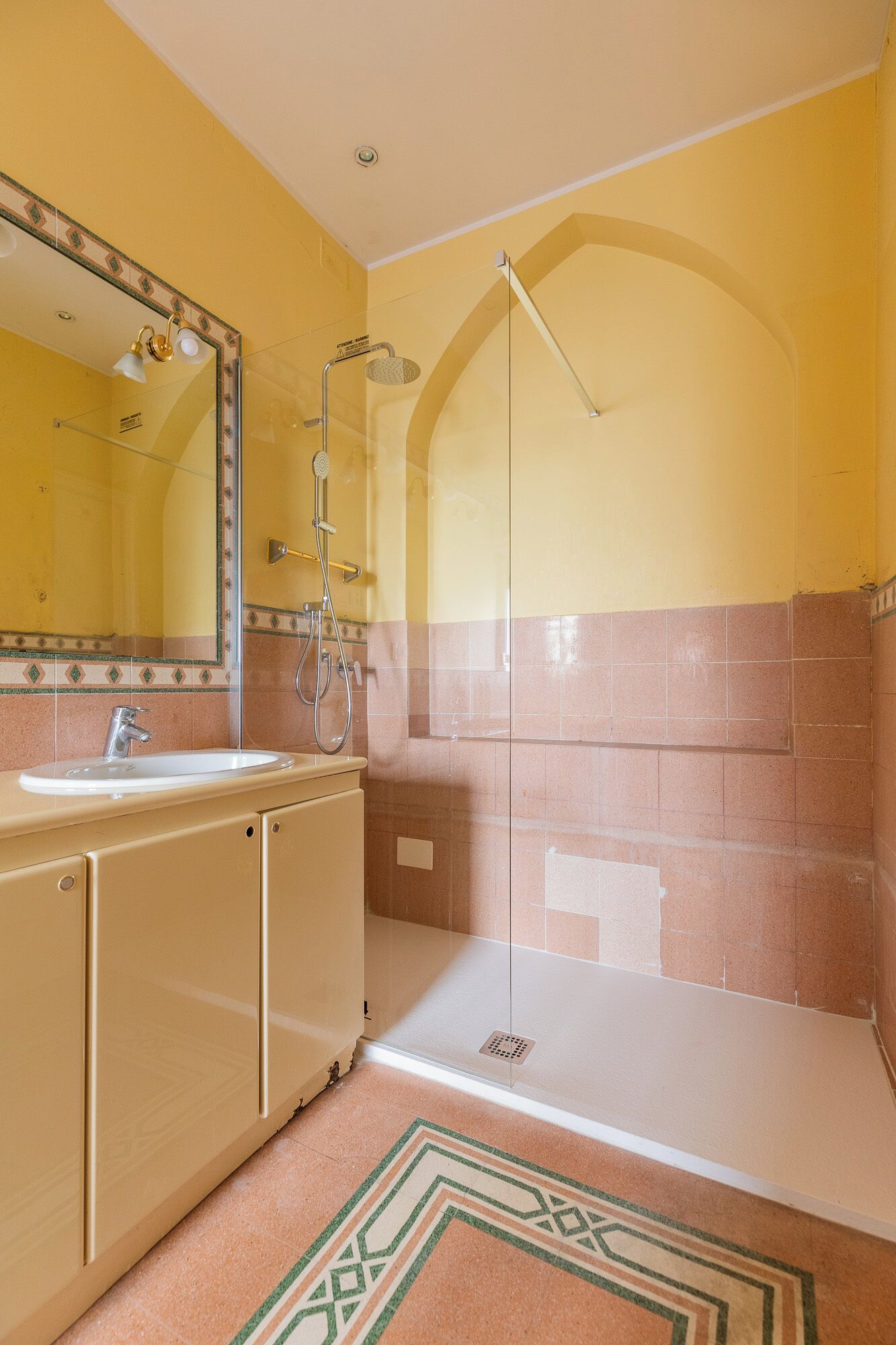 A bathroom with a shower, sink, and mirror.