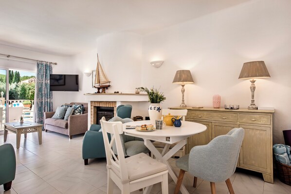 A modern living room with a fireplace, a round dining table, and comfortable seating.