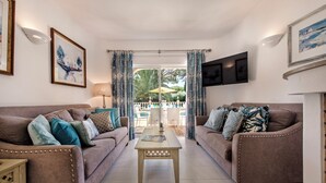 A living room with two sofas, a coffee table, and a TV mounted on the wall. - 4 Bedrooms Private Pool Close To All Amenities (Loulé)