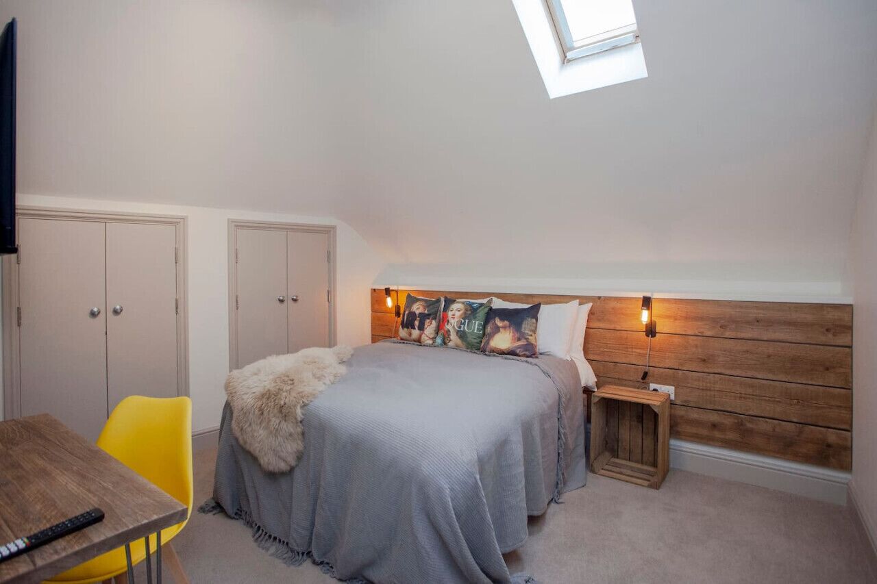 A bedroom with a bed, a small table, a chair, a nightstand, and a TV.