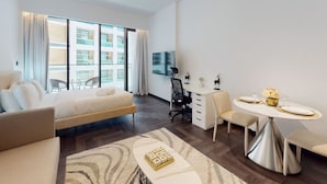 Une chambre d’hôtel moderne équipée d’un lit, d’un bureau, d’une table à manger et d’une grande fenêtre.
