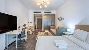Une chambre d’hôtel comprenant un lit, un bureau avec une chaise, une télévision, un canapé et une petite table avec une lampe.