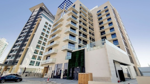 Un immeuble résidentiel à plusieurs étages, doté de balcons, d’un garage et d’une entrée sécurisée.