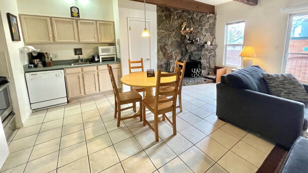 A kitchen with a dining table and chairs, a stone fireplace, a sofa, and a window with a view. - NEW LISTING! Panoramic Views At Panorama! (Breckenridge)