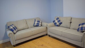 Two beige sofas with plaid pillows against a light blue wall, placed on a wooden floor. - Room 2 (Birmingham)