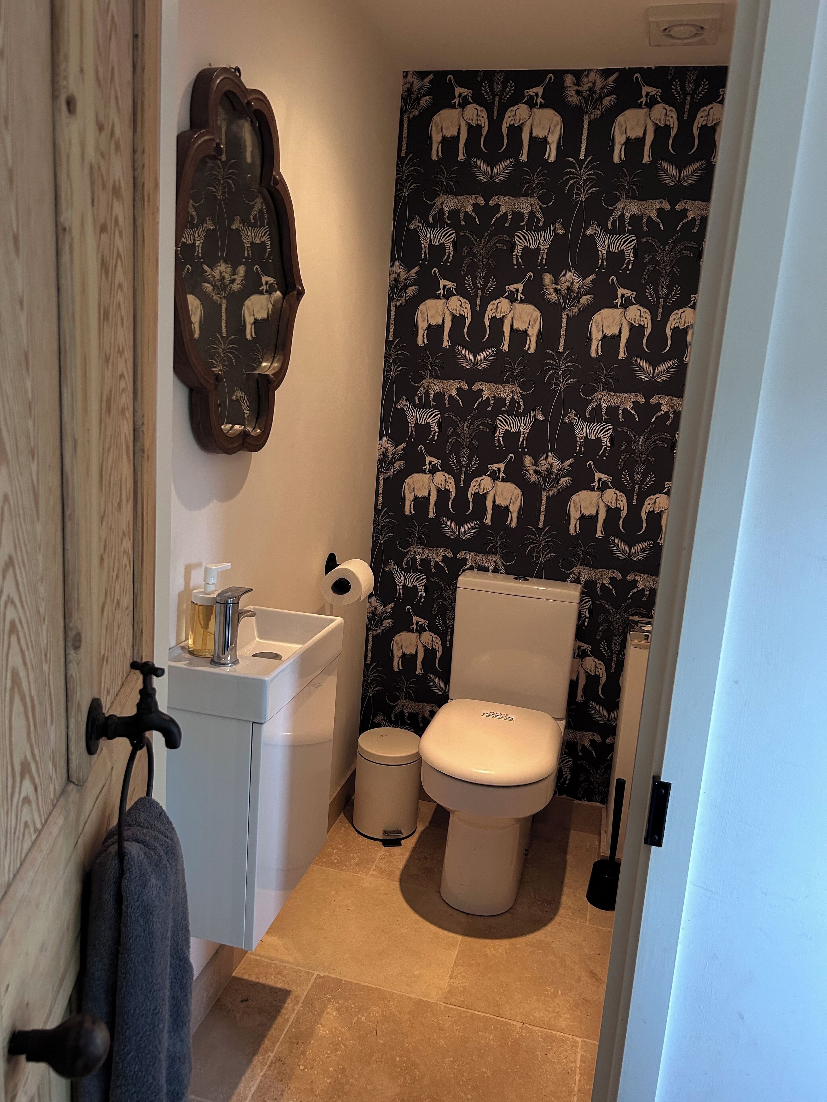 A small bathroom with a toilet, sink, and a towel hanging on the wall.
