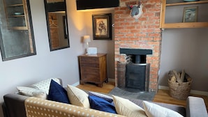Una sala de estar acogedora con una chimenea de ladrillo, un aparador de madera y un sofá con cojines decorativos.
