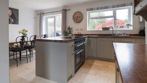 Una cocina moderna con una isla central, horno empotrado y un amplio ventanal que proporciona luz natural.