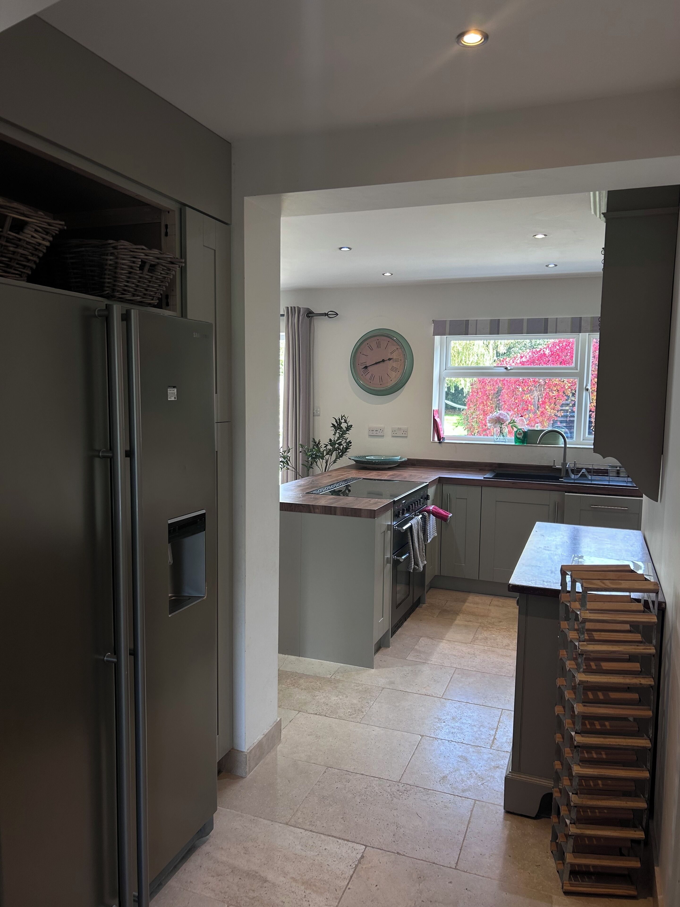 Een moderne keuken met een inbouwkoelkast, een houten aanrechtblad en een raam met uitzicht op bomen.