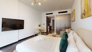 Une chambre d’hôtel moderne dotée d’un grand lit, d’un téléviseur à écran plat, d’un coin repas et d’une kitchenette.
