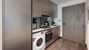 Une cuisine compacte équipée d’un lave-linge, d’une cuisinière et d’un four à micro-ondes.