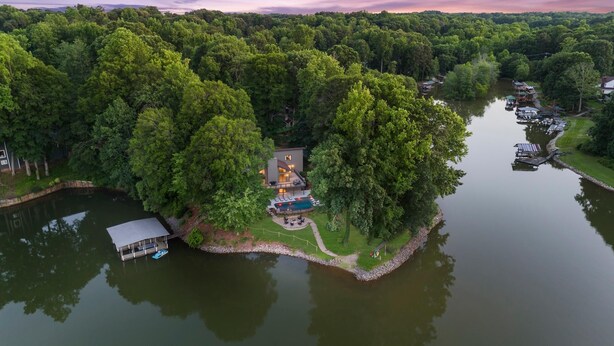 Una proprietà sul lago con una casa circondata da fitta foresta, un molo e una piscina.