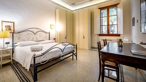 Un dormitorio con cama, mesita de noche, lámpara y ventana con persianas.