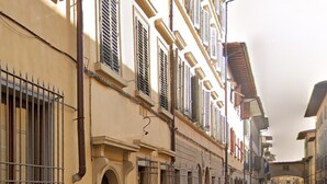 Una calle estrecha flanqueada por edificios, con puertas en arco y ventanas con rejas.