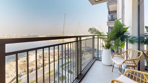 A balcony with a view of a construction site, potted plants, and wicker furniture.