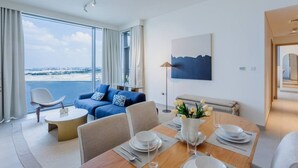 A modern hotel room with a dining area, a sofa, and a view of the sea.