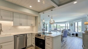 A modern kitchen with white cabinetry, stainless steel appliances, and a large island. - Sunset Rentals | Yacht Club 7548 | Shelter Cove (Hilton Head Island)