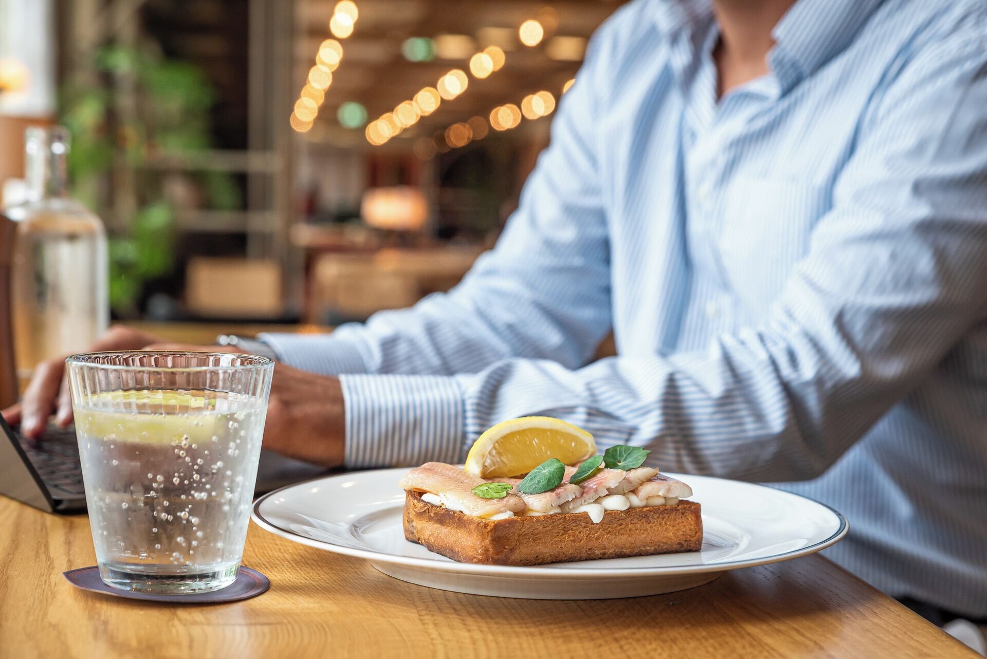 A person sitting at a table with a plate of food and a glass of water.