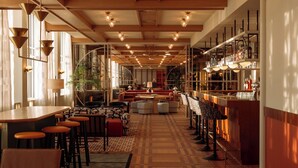 A spacious bar area with high ceilings, wooden beams, and a long counter with stools. - De Plesman Hotel The Hague (The Hague)