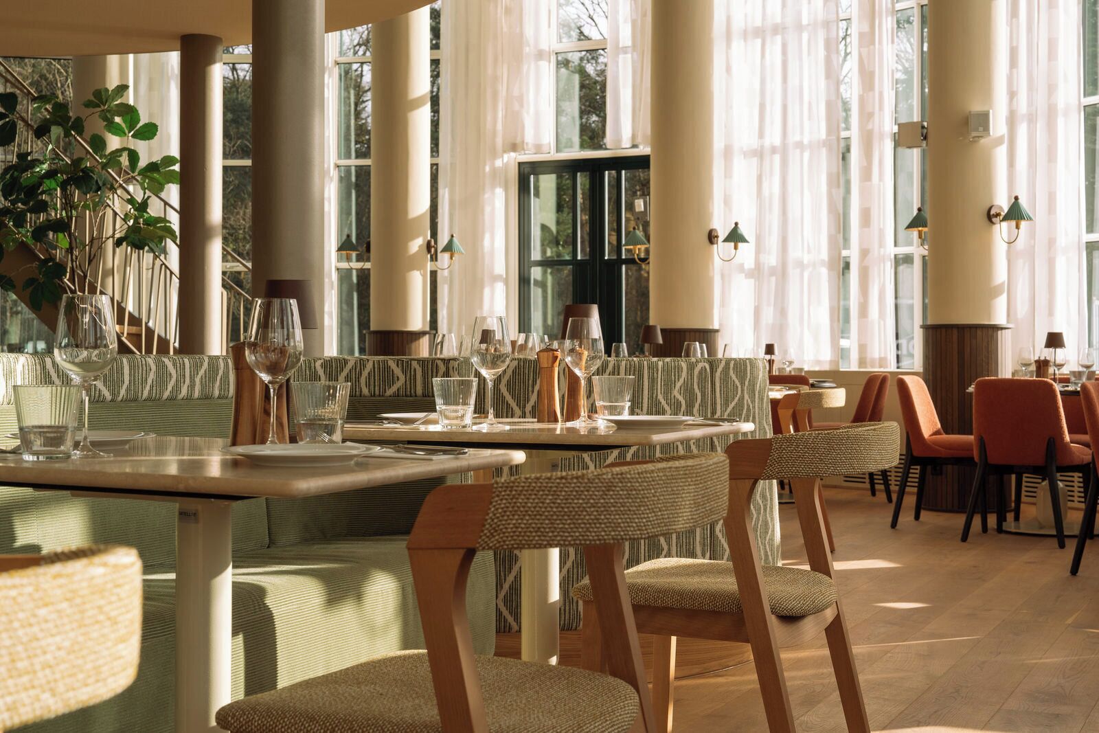 Un restaurant avec de hauts plafonds, de grandes fenêtres et différents types de sièges, notamment des tables et des chaises.