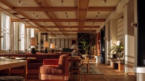 A spacious room with wooden beams, large windows, and a variety of seating arrangements including sofas and tables. - De Plesman Hotel The Hague (The Hague)