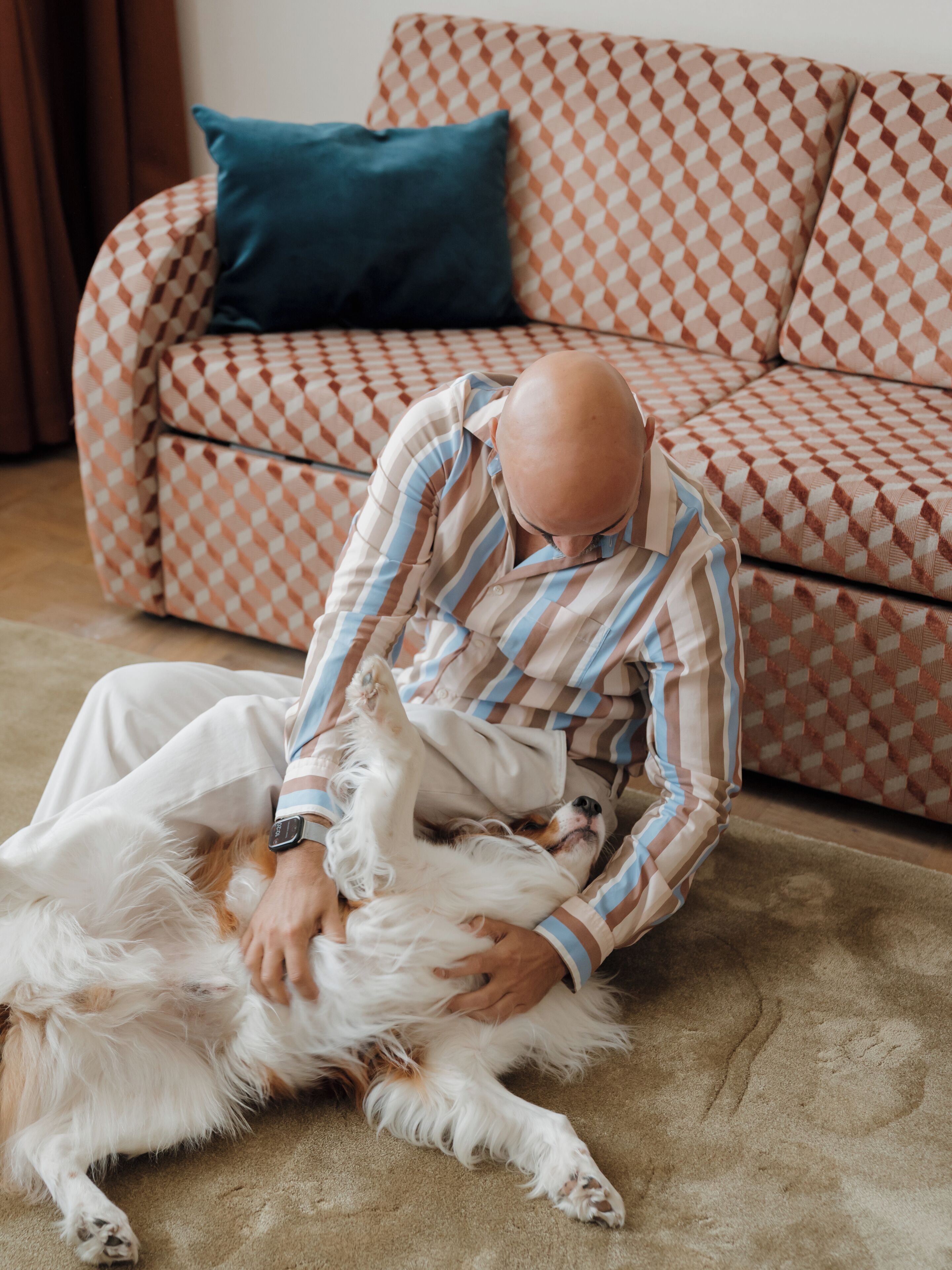 A person sitting on a patterned sofa with a dog lying beside them.