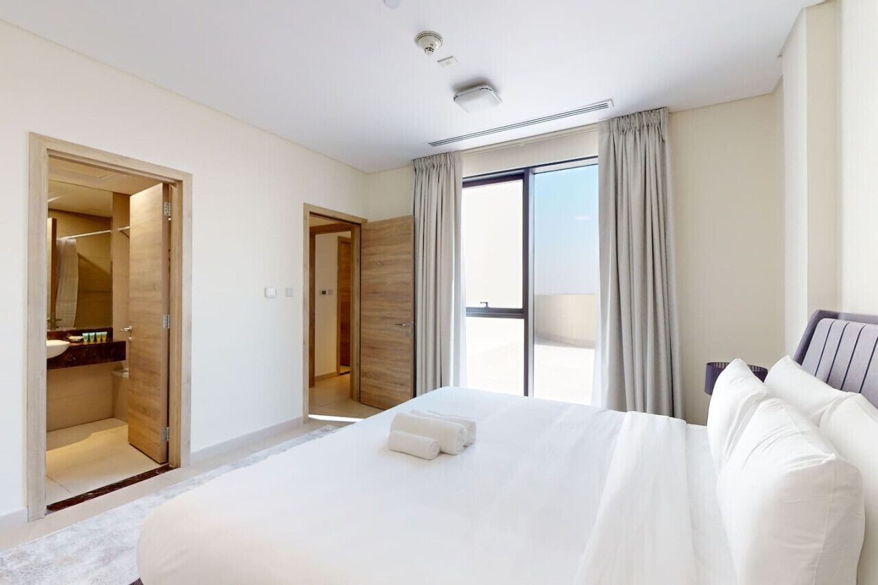 Een moderne hotelkamer met een groot bed, een inloopkast en uitzicht op het omliggende landschap.