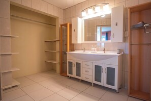 A bathroom with a white sink, mirror, and cabinets. There are shelves and a wooden door. - Beautiful Luxury Home in Seroe Colorado (San Nicolas)