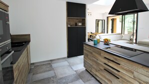 Una cocina moderna con horno integrado, un armario de madera y un ventanal amplio.