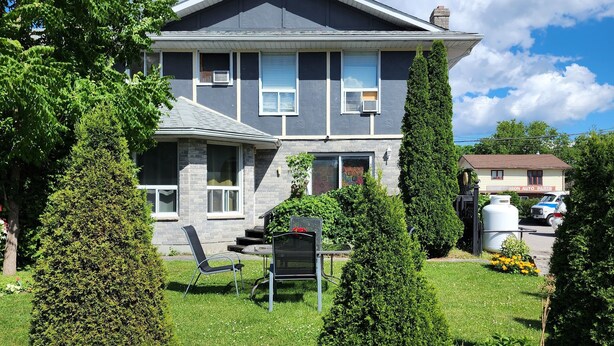 A two-story house with a stone facade, a front porch, and a well-maintained lawn. - Princess Motel  (Kawartha Lakes)