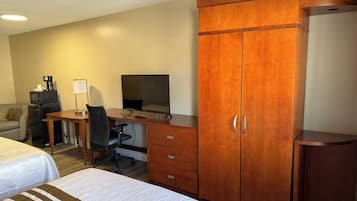 Une chambre d’hôtel avec deux lits, un bureau avec un ordinateur, un four à micro-ondes, une machine à café, une télévision et une armoire.