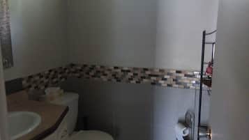 Un baño pequeño con inodoro, lavabo y ventana sobre el inodoro.