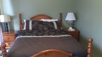 A bedroom with a wooden bed, two bedside tables with lamps, and a carpeted floor.