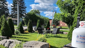 A residential area with a lawn, outdoor seating, and a propane tank. - Princess Motel  (Kawartha Lakes)