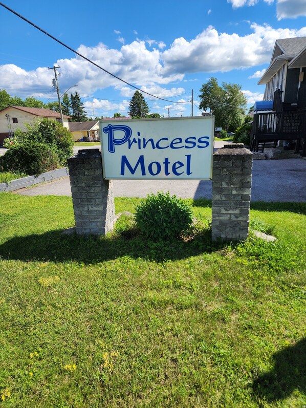 A sign for the Princess Motel with a clear sky and greenery in the background. - Princess Motel (Kawartha Lakes)