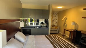 A hotel room with a bed, a desk, a chair, a kitchenette, and a sofa. - Princess Motel  (Kawartha Lakes)