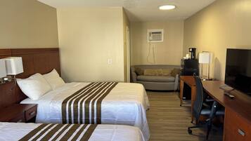 Een hotelkamer met twee bedden, een bureau, een televisie en een bank.