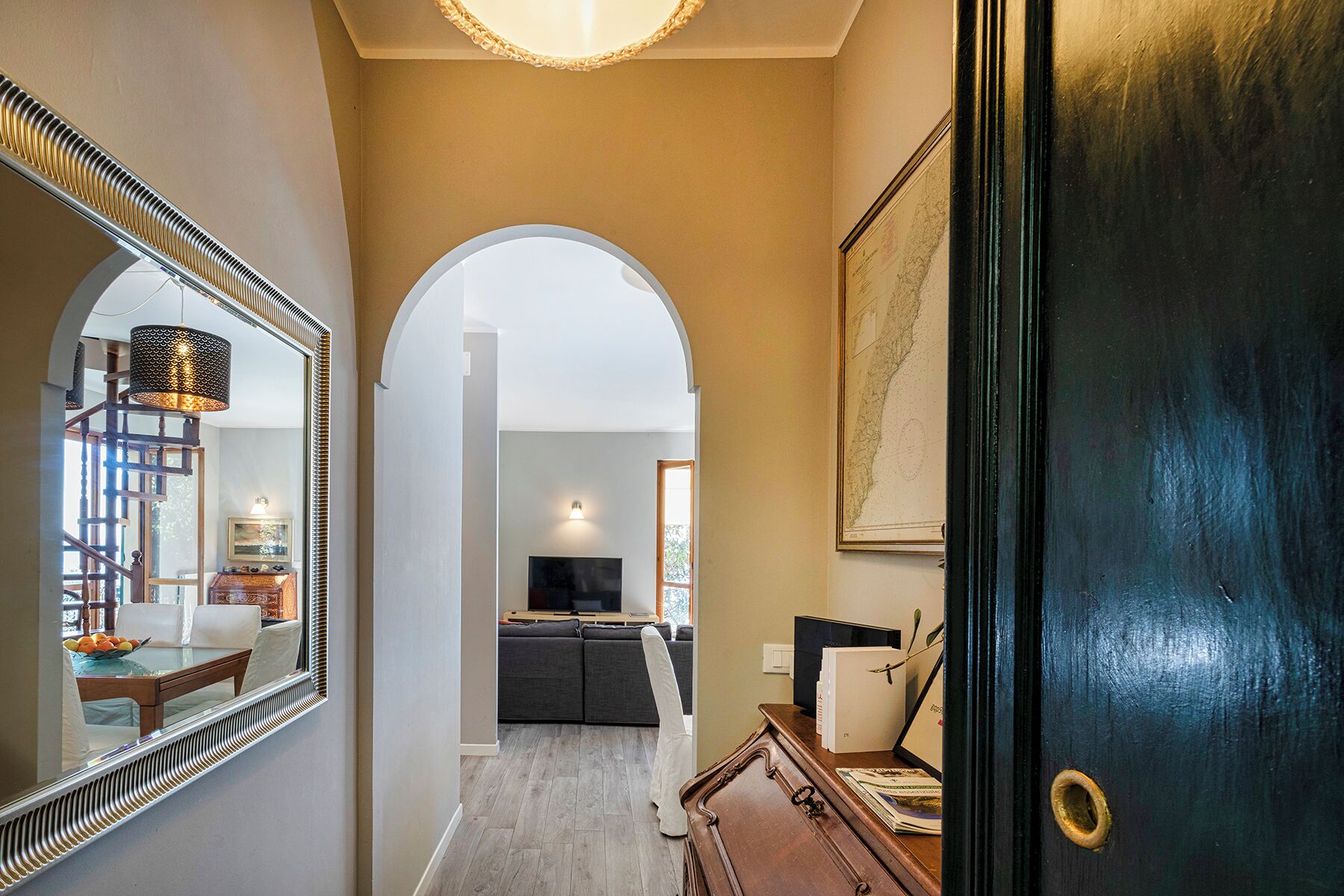 A hallway with a mirror, a dark wooden door, and a framed map on the wall.