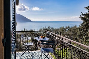 Ein Balkon mit Tisch und Stühlen, mit Blick auf ein Gewässer und einen Berg.