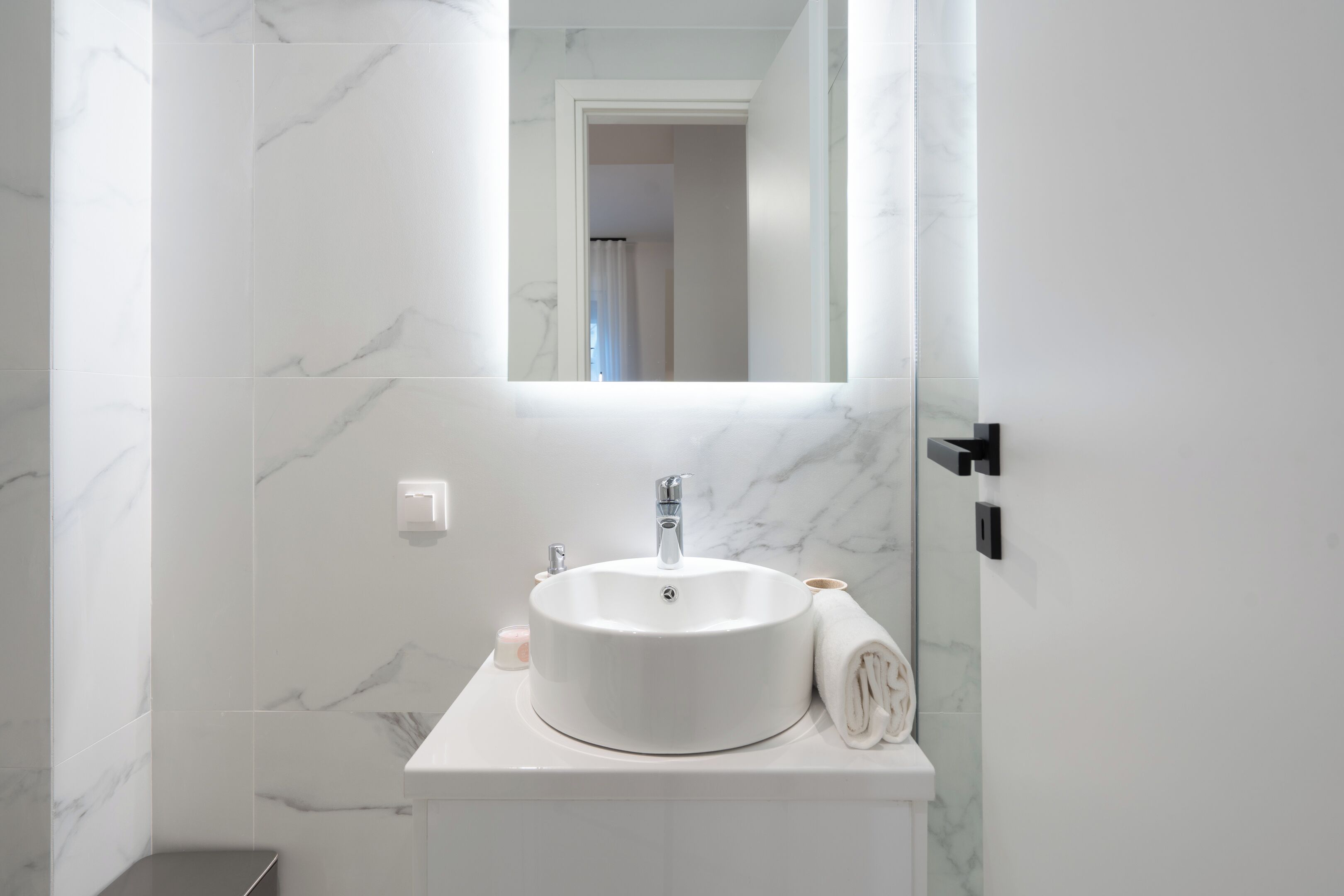 Une salle de bain avec un lavabo en marbre blanc, un miroir au-dessus et une serviette posée sur le comptoir.