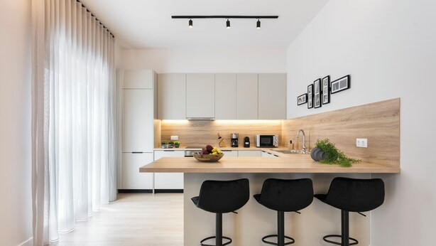 A modern kitchen with a wooden countertop, three black bar stools, and a built-in sink. - Athenian Modern & Luxury Apartments (Vyronas)