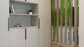 Un interior moderno con un armario blanco, estanterías con libros y una planta, y un banco de madera con verdor vertical.