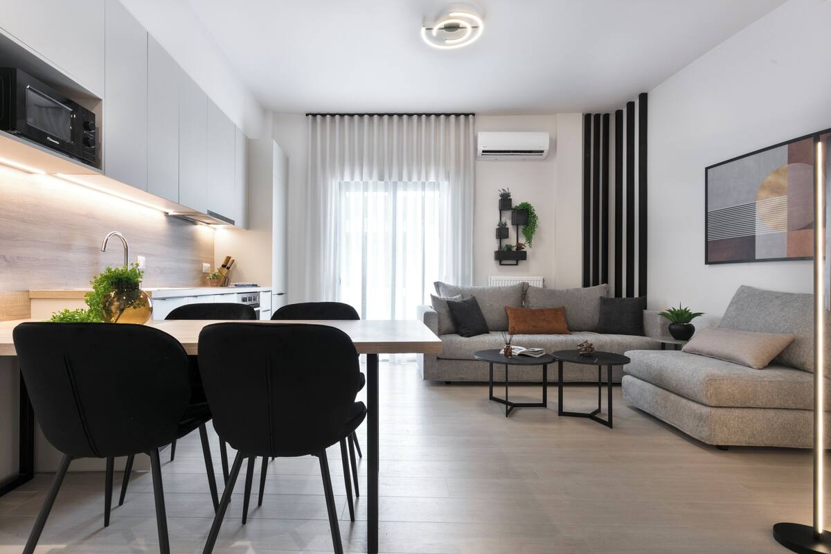 Un salon moderne comprenant un canapé, une table à manger avec des chaises et un coin cuisine équipé d’un four à micro-ondes.