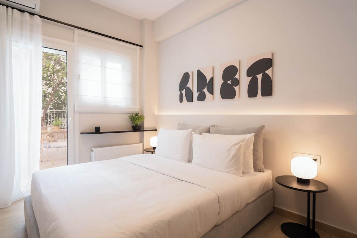 Une chambre moderne avec un grand lit, une table de chevet avec une lampe et des œuvres d’art abstraites accrochées au mur.