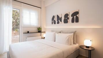 Une chambre moderne avec un grand lit, une table de chevet avec une lampe et des œuvres d’art abstraites accrochées au mur.