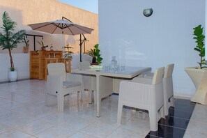 Eine Terrasse im Freien mit Tisch und Stühlen, umgeben von Blumentöpfen.