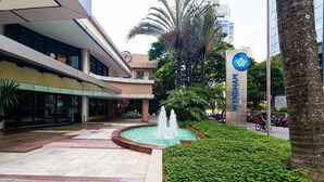 A modern building with a fountain in the center, surrounded by greenery and a paved walkway. - Vossa Bossa Berrini (São Paulo)