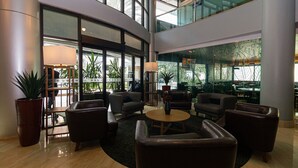 A spacious lobby with leather seating, a central coffee table, and large windows offering views of the interior. - Vossa Bossa Berrini (São Paulo)