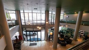 A spacious lobby with a central seating area, large windows, and a glass elevator shaft. - Vossa Bossa Berrini (São Paulo)